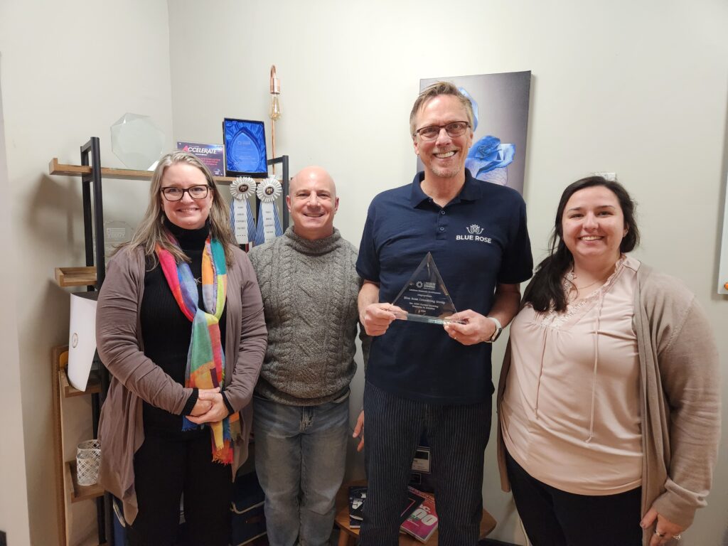 Four people smiling and one of them holds a crystal plaque for Inc 5000
